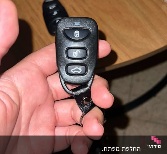 מפתח רכב עם שלט שלושה כפתורים ביד